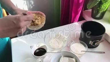 蓝莓芝士蛋糕。 一个女人正在把饼干碎屑和黄油混合在一起。